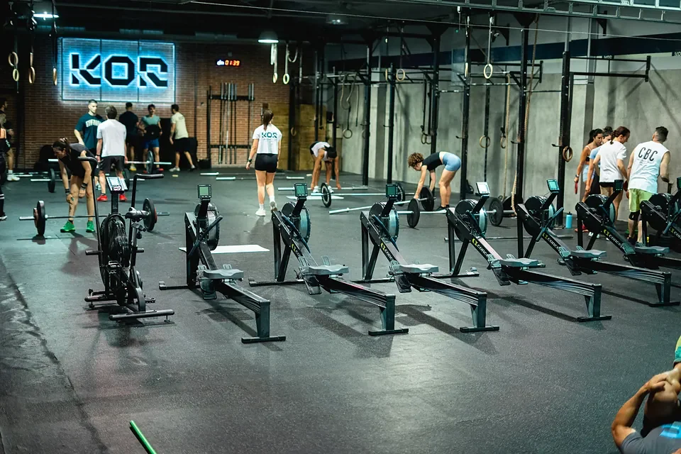 Clase de CrossFit en grupo en KOR Training Club, entrenando con remos y bicicletas de asalto
